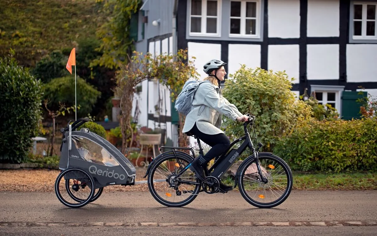 Bild Frau auf dem Fahrrad mit Kinderfahrradanhänger